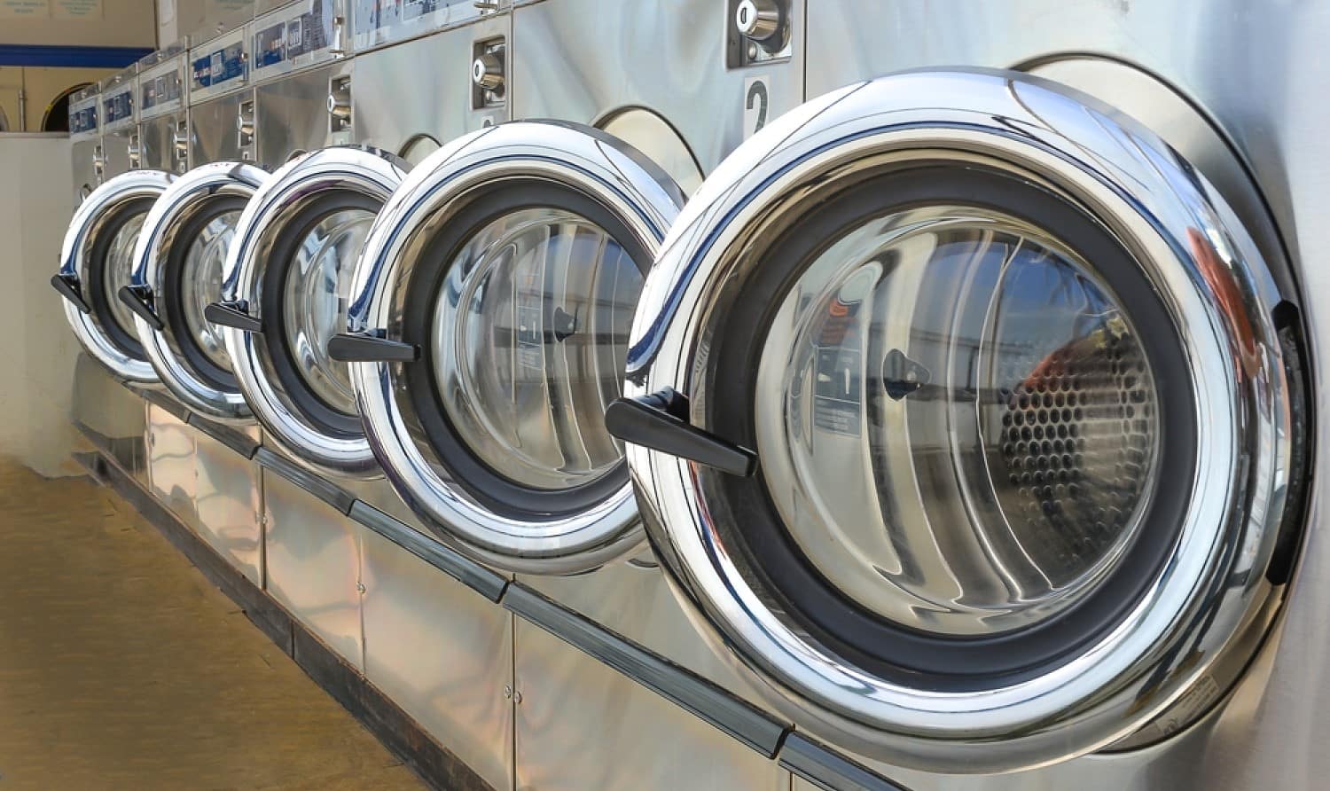 stock-photo-row-of-industrial-laundry-machines-in-laundromat-499040032